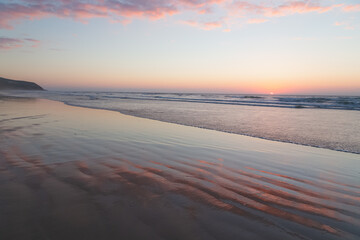 Sunset with patterns in the sand at the beach outside the seaside fishing village of Tafedna in Essaouira province, Morocco.