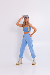 Studio photo of a young attractive woman in a warm blue fashionable suit wearing virtual reality glasses on a white background