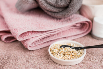 Fototapeta na wymiar spa still life with towel and natural scrub from oatmeal and black ceramic spoon
