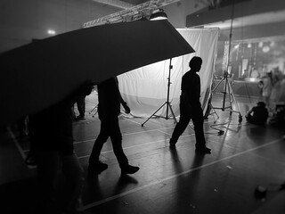Behind the scenes of music video shooting production crew team silhouette and camera equipment in studio. Black and White.