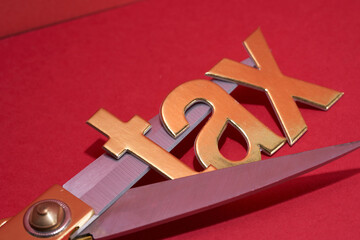 single word tax and gold colored scissors on the red background