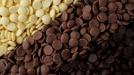 chocolate chips from white, milk, black chocolate top view. confectionery concept