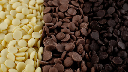 chocolate chips from white, milk, black chocolate top view. confectionery concept