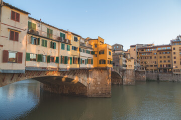 Fototapeta na wymiar The historic and popular tourist attraction Ponte Vecchio bridge perched over the River Arno in Florence, Italy on a clear sunny day in Tuscany.