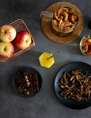 Composition of tea drinking. On a dark background, tea with dried fruits, apples, honey and chocolate. Antiviral kit. View from above 