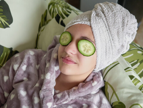 Young girl at home with cucumber slices on her eyes, beauty treatment at home