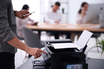 Employee using modern printer in office, closeup - obrazy, fototapety, plakaty