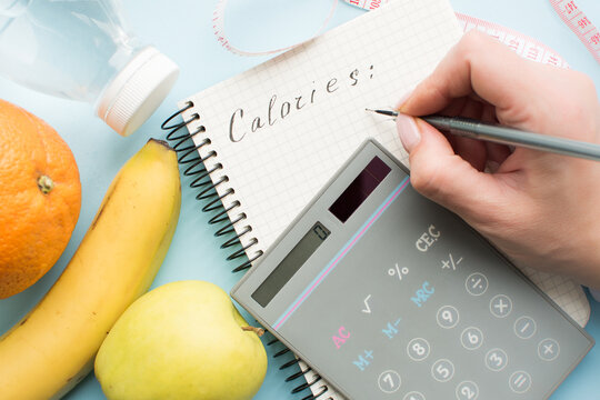 Woman calculating calories in paper notebook
