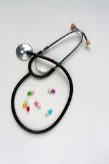 a stethoscope and some colorful pills on white background