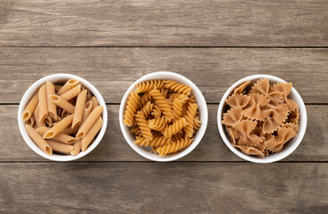 Assorted whole wheat pasta on bowls over wooden table
