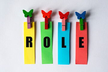 ROLE - word on multicolored stripes with clothespins on a white background