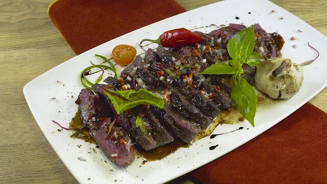 Pieces of steak medium rare with vegetables and herbs. Sliding camera close up1