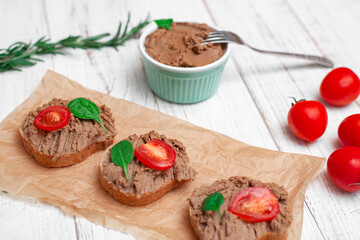 Chicken liver pate. Sandwiches, canapes with pate with cherry tomatoes on a white wooden background.