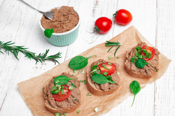 Sandwiches, canapes with chicken pate, tomatoes. On a white wooden background.