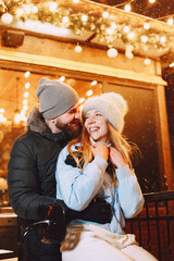 Winter holidays conception. Outdoor night portrait of young couple. Posing in street of European city.