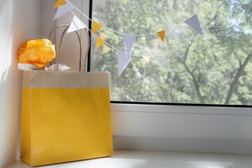 View of the yellow bag with a gift on the window. Holiday concept, background.