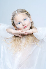 Portrait of a little beautiful girl. A fabulous image of a robot or an alien. Beautiful white makeup.