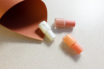 cosmetic bottles with nail polish on
 decorative colored paper concept of color selection for manicure