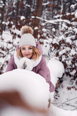 A beautiful girl walks through the winter forest. Female portrait. A secluded walk. Snow in the forest.