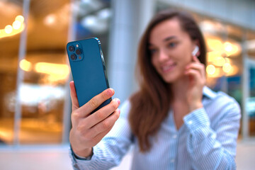 Modern happy casual smart millennial woman using smartphone for video call and remotely chatting online