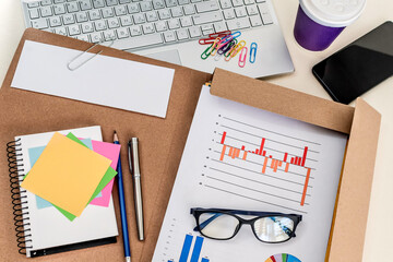 Office desk workplace with laptop, charts, smart phone and coffee. Top view