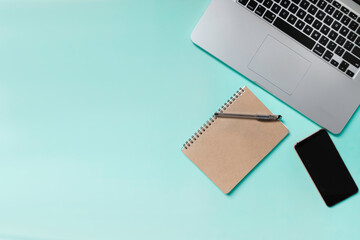 Office stuff, laptop, notebook, pen and smartphone on blue pastel color background for business and education concept. Top view with copy space.