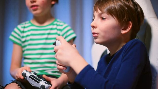 Close-up of a teenager's face during a video game. He chews gum, relaxes emotions. The joy of doing what you love in your free time. In the hands is a joystick.