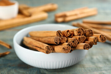 Aromatic cinnamon sticks on blue wooden table, closeup