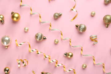 Shiny serpentine streamers and Christmas balls on pink background, flat lay