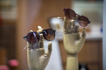 Closeup of sun glasses on wooden hands presentation in an optician store showroom