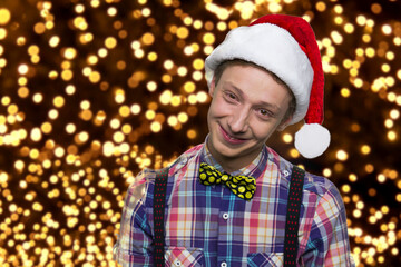 Positive young boy in santa hat. European boy with bowtie on his shirt is smiling. Happy new year....