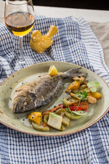 whole seabass fish grilled with vegetables, herbs and glass of white wine