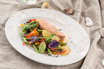 salmon fillets steamed on a plate with vegetables and lemon on the table