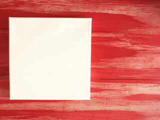 Invitation concept with a blank canvas on a red wooden background