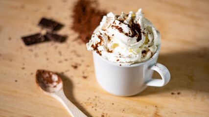 Primer plano de una taza de café con crema batida de cacao en polvo, canela y chocolate