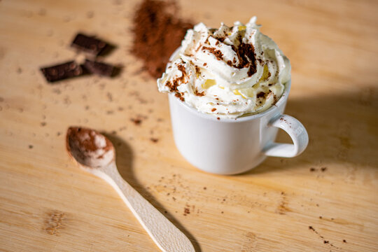 Primer plano de una taza de caf&eacute; con crema batida de cacao en polvo, canela y chocolate
