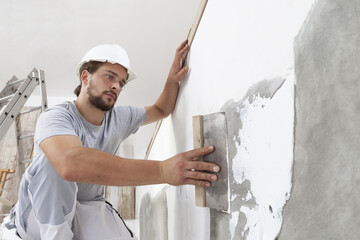 Hands man plasterer construction worker at work with trowel, plastering a wall, closeup