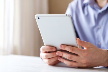 Tablet in the hands of a young man against the background of a blue shirt - Businessman uses a tablet to read and view content in social networks - Concept of modern technologies