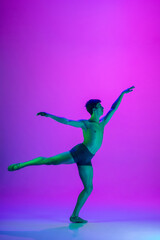 Fototapeta na wymiar Feelings. Young and graceful ballet dancer on purple studio background in neon light. Art, motion, action, flexibility, inspiration concept. Flexible caucasian ballet dancer, moves in glow.