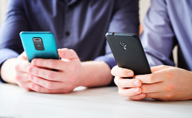Two friends side by side use phones to type text messages - Hands and phone close up - Concept of modern technologies and content in social networks