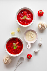 Top view of the traditional Ukrainian borscht or soup with beets, potatoes, tomatoes, meat in bowls on a white background. Top view. Free copy space.