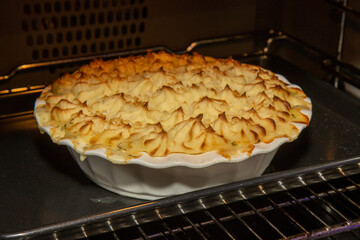 A delicious fish and seafood pie, topped with golden brown mash potato in the oven being baked till it is golden brown