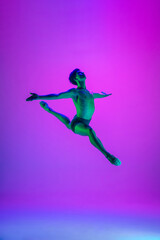 Fototapeta na wymiar Weightless. Young and graceful ballet dancer on purple studio background in neon light. Art, motion, action, flexibility, inspiration concept. Flexible caucasian ballet dancer, moves in glow.