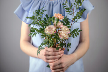 A woman in a blue dress is holding a small tenderness bouquet of flowers. Concept of spring, summer nice romantic mood