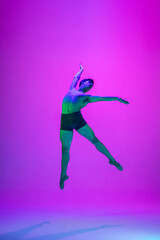 Fototapeta na wymiar Feelings. Young and graceful ballet dancer on purple studio background in neon light. Art, motion, action, flexibility, inspiration concept. Flexible caucasian ballet dancer, moves in glow.