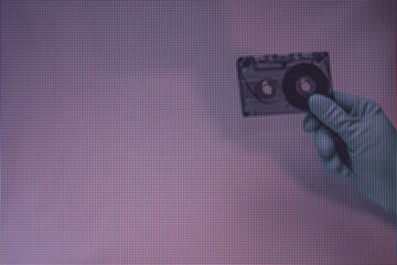 Green Hand holding audio cassette tape in the color light. Beautiful minimal in neon light....