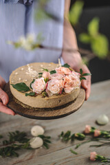 Woman is holding in her hands a beautiful raw mousse cake decorated with tenderness flowers. Concept of a romantic atmosphere and spring mood