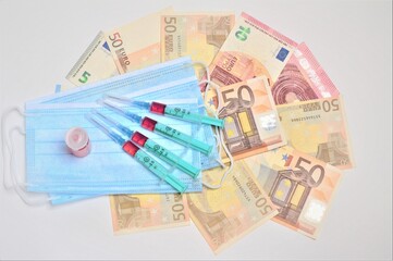 Syringes with medicine on a medical mask and money.