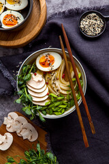 Bowl of asian ramen soup with noodles, spring onion, sliced egg and mushrooms on black table. Japanese dish in black.
- 412247514