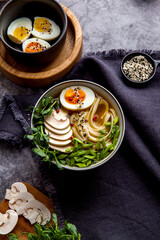 Bowl of asian ramen soup with noodles, spring onion, sliced egg and mushrooms on black table. Japanese dish in black.
- 412247590